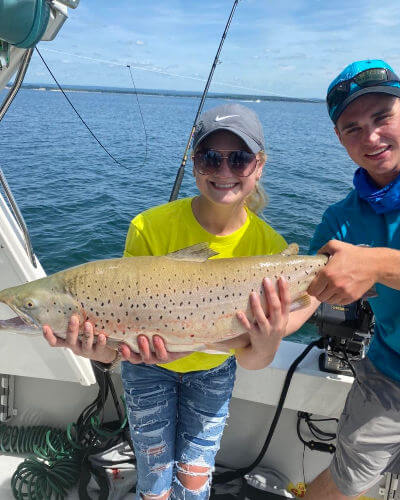 Happy young lady angler shows off her big brown trout.